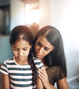 A woman comforts a young child who looks sad